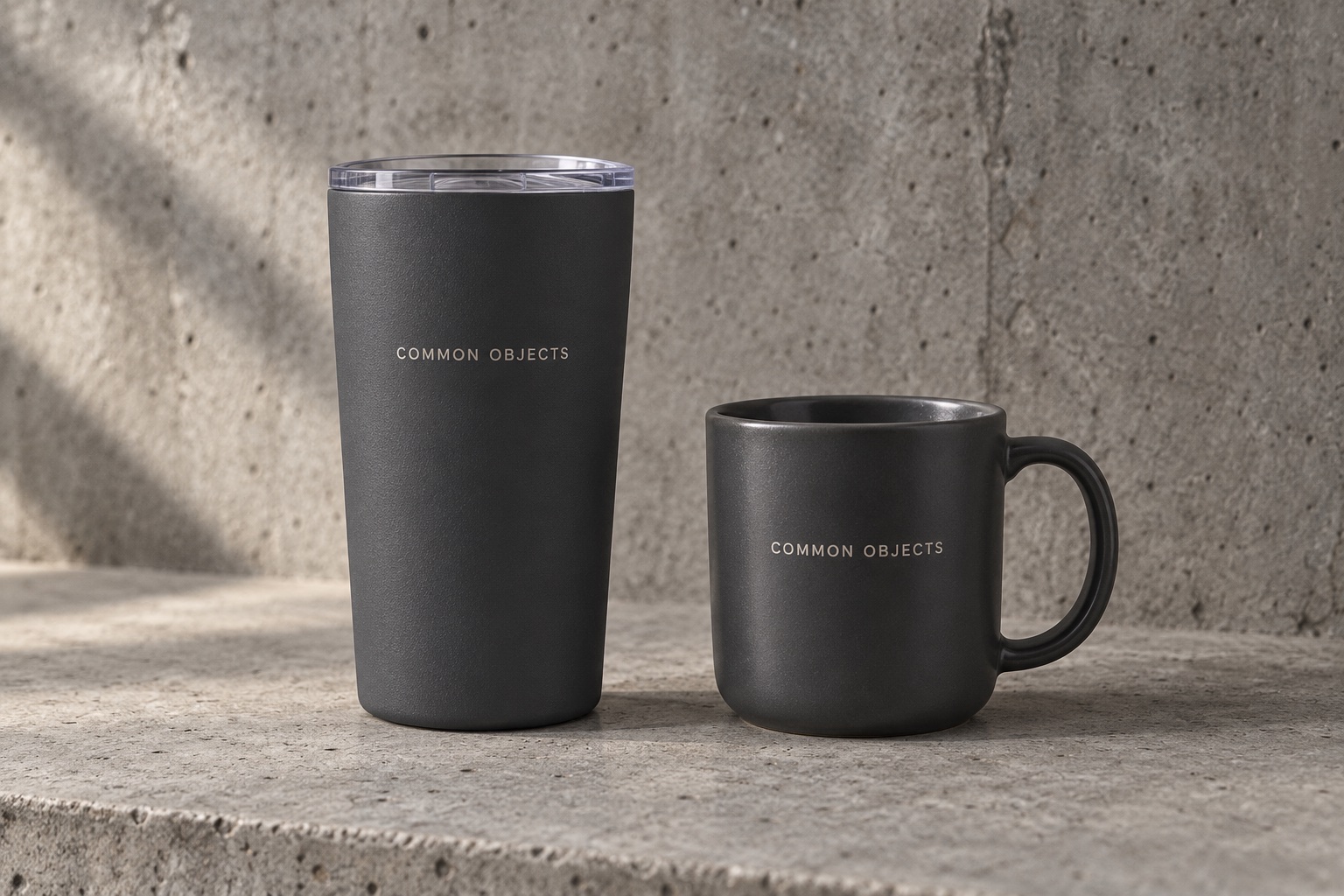 Charcoal Common Objects tumbler and ceramic coffee mug on concrete