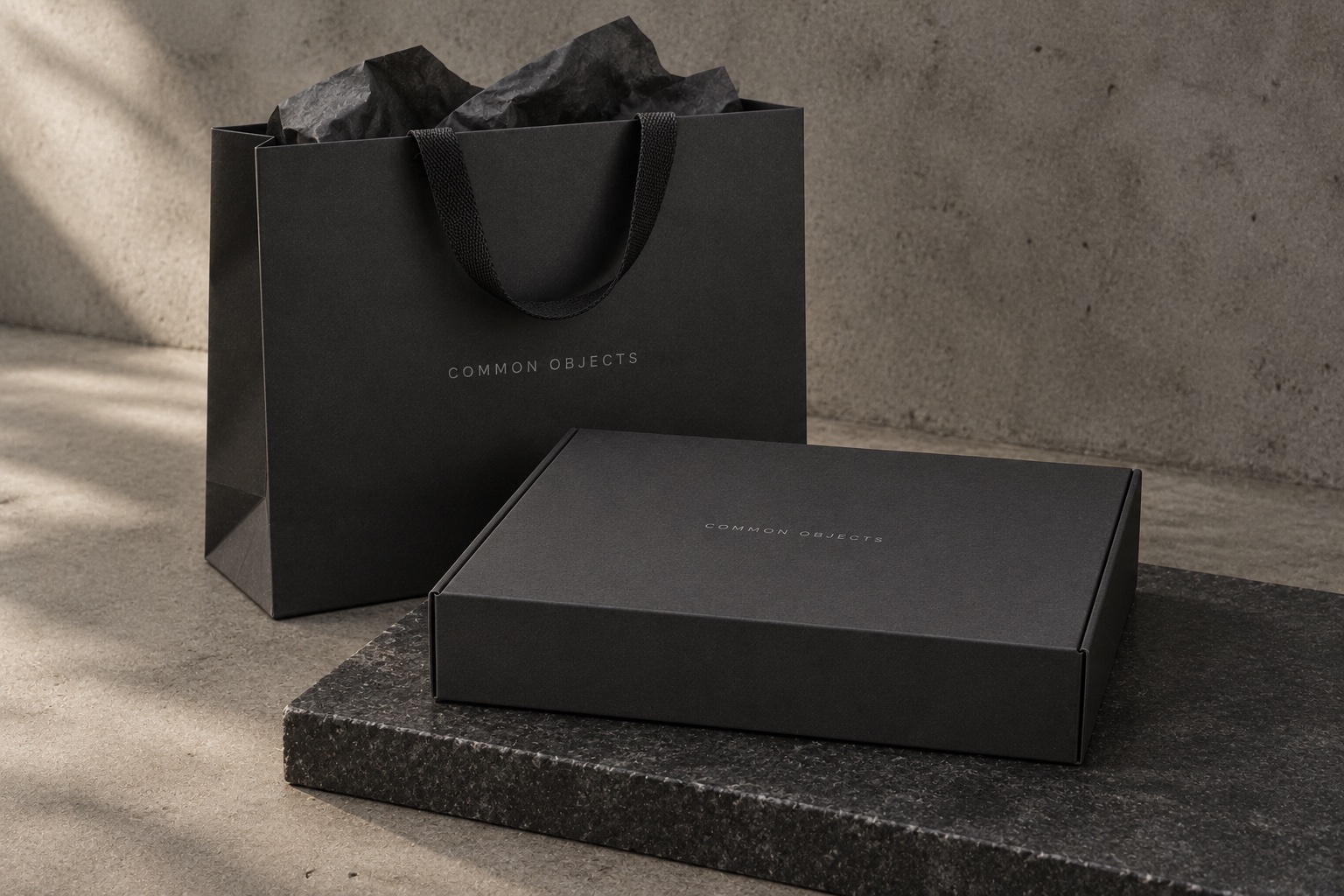 Black Common Objects box and textured shopping bag on stone