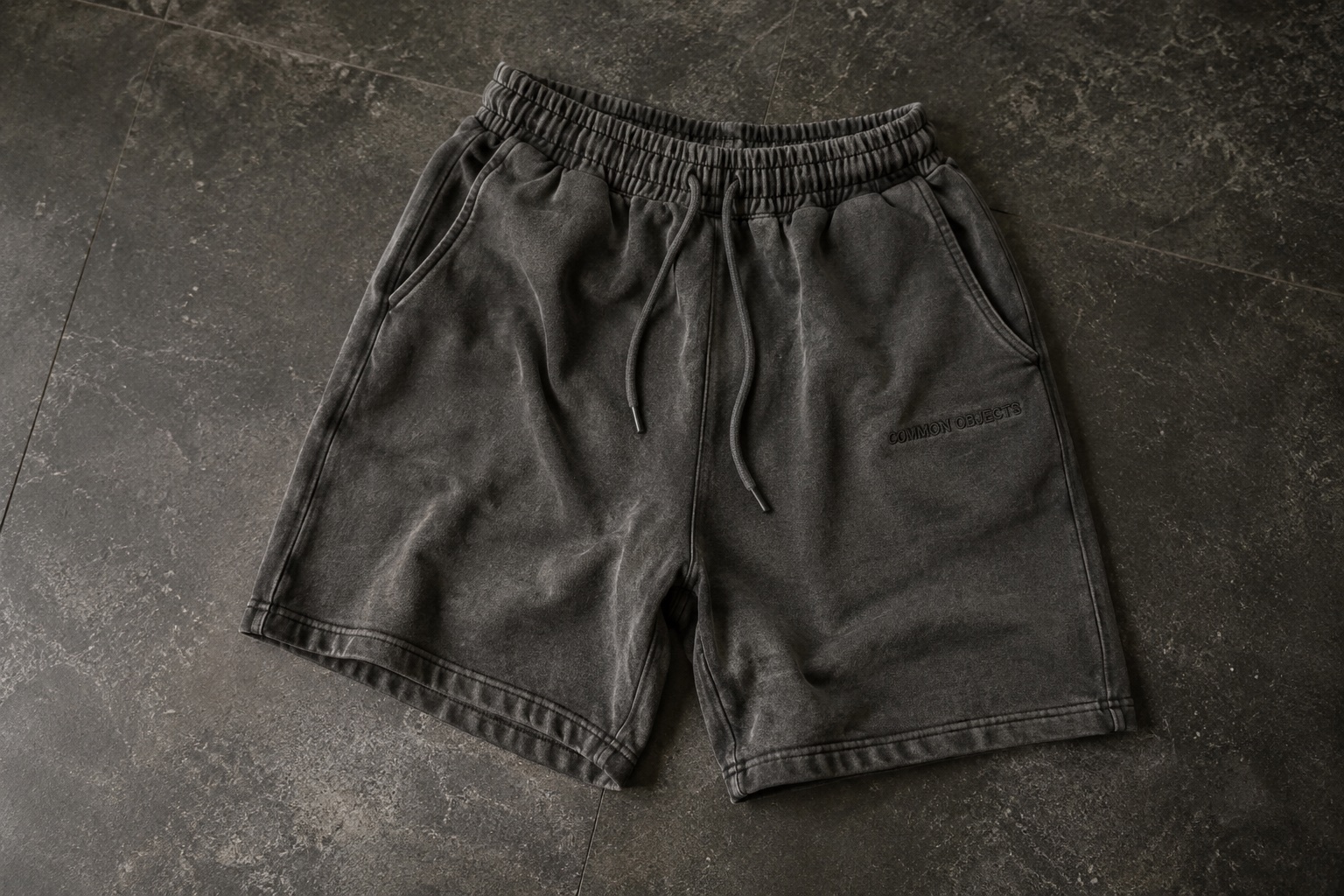 Washed charcoal Common Objects sweat shorts on dark stone